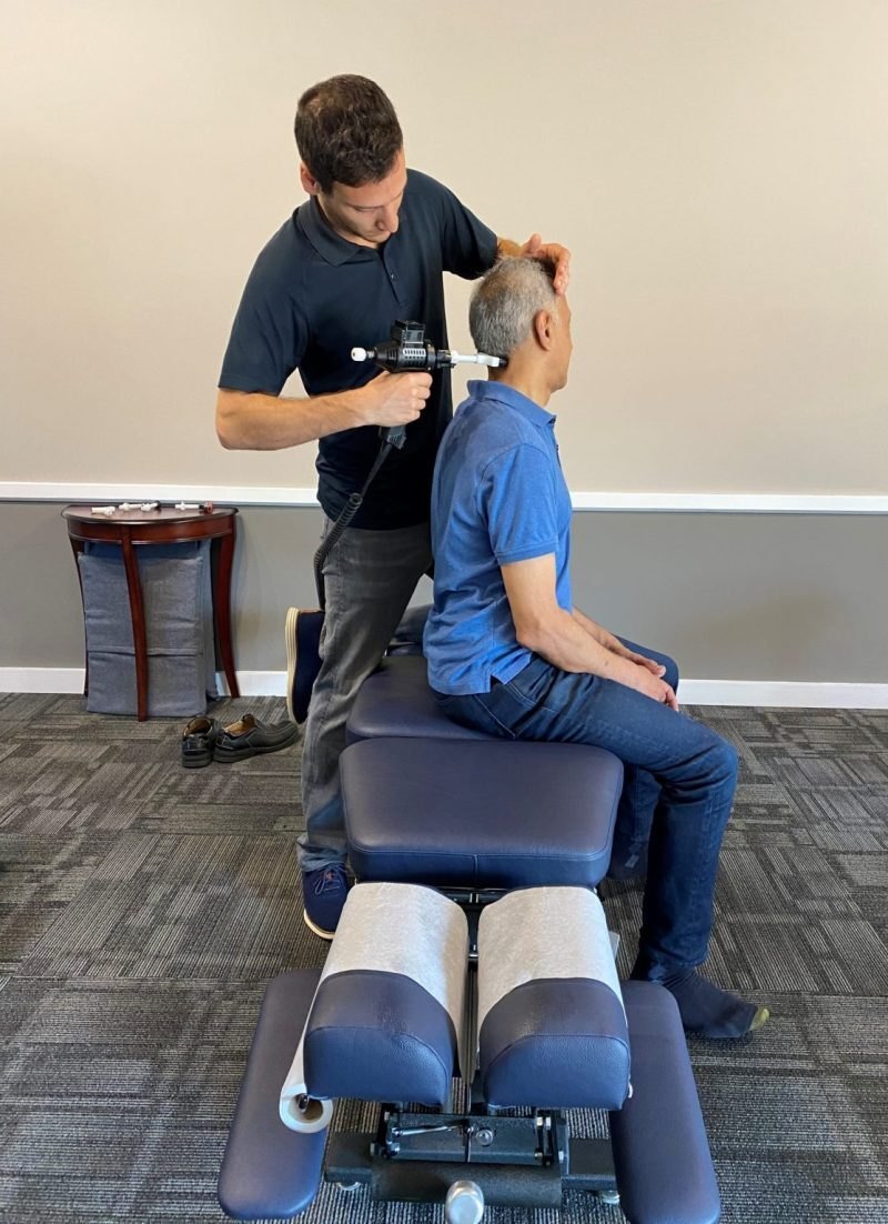 Dr. Cory Plasker delivering an instrument adjustment to a seated patient